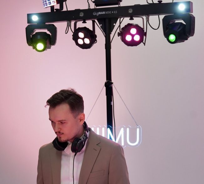 DJ NIIMU im Borussia Park DJ an einem Mischpult in einem Eventraum mit Bühnenlichtern.