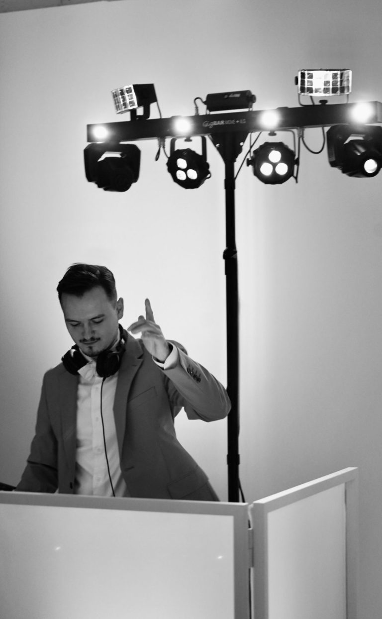 DJ NIIMU EVENT DJ steht an einem Mischpult und bedient Plattenspieler in einem Club. DJ NIIMU im Borussia Park